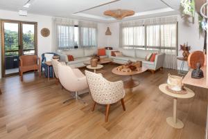 uma sala de estar com um sofá, mesas e cadeiras em Studio Smart Farol da Barra Completo e Funcional em Salvador