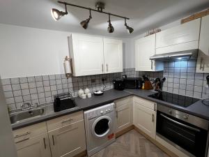 uma cozinha com armários brancos e uma máquina de lavar roupa em The Farthings, Romsey Apartment em Romsey