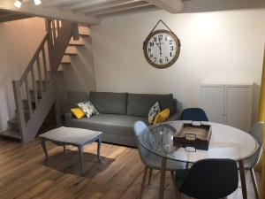 a living room with a couch and a clock on the wall at Winnipeg in Colombiers-sur-Seulles