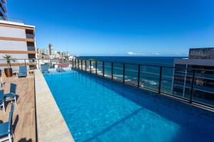 uma piscina no topo de um edifício com o oceano em Studio Smart Farol da Barra Completo e Funcional em Salvador