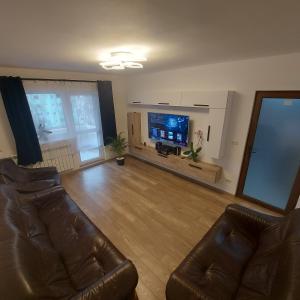 ein Wohnzimmer mit 2 Ledersesseln und einem Flachbild-TV in der Unterkunft Apartament AntoniaS in Făgăraş