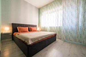 ein Schlafzimmer mit einem Bett mit orangefarbenen Kissen und einem Fenster in der Unterkunft Студио Римски Стадион in Plowdiw