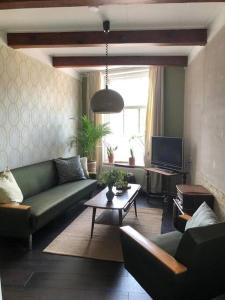 a living room with a green couch and a tv at De Scheve Deur in Vollenhove