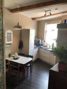 a kitchen with a table and chairs and a refrigerator at De Scheve Deur in Vollenhove