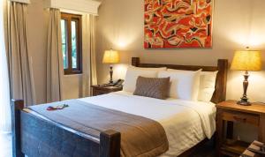 a bedroom with a bed with two lamps and a painting at Valle Escondido Resort Golf & Spa in Boquete