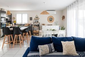 a living room with a blue couch and a kitchen at Agréable maison avec extérieur in Parentis-en-Born