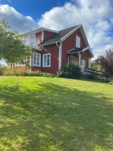 uma casa vermelha com um grande relvado em frente em Naturnära hus utanför Reftele närhet till Isaberg och High Chaparral em Reftele