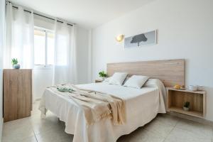 Dormitorio blanco con cama grande y cabecero de madera en Alea Rentals - Acquamarina, en La Pineda