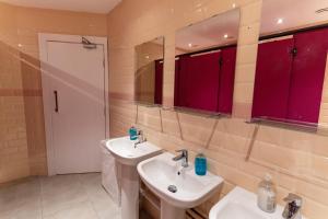 La salle de bains est pourvue de 2 lavabos et de placards rouges. dans l'établissement Hostelle - women only hostel London, à Londres