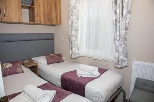 a small room with two beds and a window at Nature Haven Hot Tub Lodge 30 Cameron, St Andrews in St. Andrews