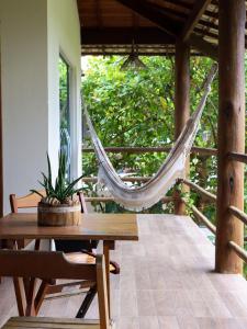 a hammock on a porch with a table and chairs at Flats Maui in Barra Grande