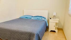 1 dormitorio con 1 cama con almohadas azules y mesita de noche en Departamento Avenida Bolognesi Tacna, en Tacna