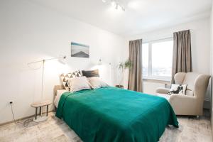 Un dormitorio blanco con una cama verde y una silla en Light Amber apartment en Cēsis