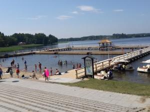 a group of people on a beach near a pier at holiday home, Kretowiny in Kretowiny