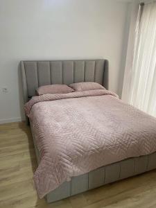 een bed met roze dekbed en kussens in een slaapkamer bij Bego Residence in Bitola