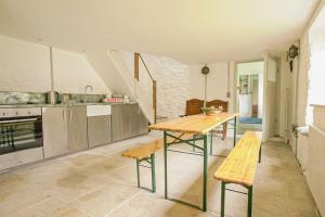 a kitchen with a table and benches in a room at Lower Godney Little House in Wells