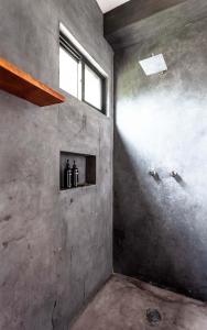 een kamer met een betonnen muur en een raam bij Che Puerto Escondido Hostel & Bar Adults Only in Puerto Escondido