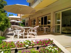 a patio with chairs and tables and flowers at B&b villa lambusta in Cesenatico