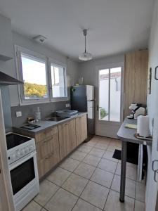 eine Küche mit Holzschränken und einem Kühlschrank in der Unterkunft Ma maison au bord de la mer in Saint-Hilaire-de-Riez