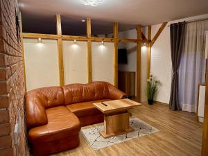 a living room with a brown leather couch and a table at Apartamenty Grodowa 2 in Gliwice