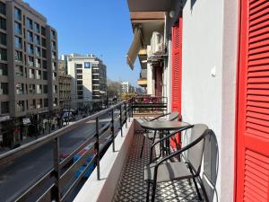 einen Balkon mit Tischen und Stühlen in einer Stadtstraße in der Unterkunft Satus Finem Egnatia's Luxury Apartment in Thessaloniki