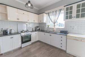 a white kitchen with white cabinets and a window at Dion House in Psalidi