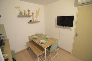 a small room with a table and chairs and a television at [Le Bohème] T2-Wifi-Calme-Parking in Lourdes