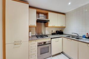 a kitchen with white cabinets and a stove top oven at Apartment in the heart of London in London