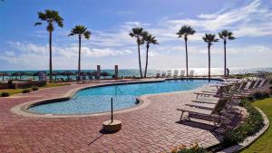 a swimming pool with benches and palm trees next to the beach at Princesa de Penasco B208 - Family Beach Getaway in Puerto Peñasco