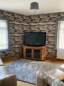 uma sala de estar com uma televisão de ecrã plano numa parede de tijolos em Masons Nook 292 Mansfield Road NG174HR em Skegby