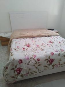 a bed with a floral comforter on top of it at Appartement Luxueux in Dakar