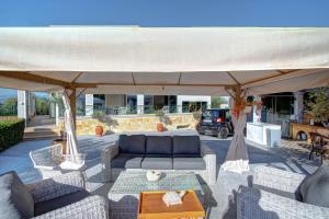 a patio with a couch and chairs under a large umbrella at The Love Villa in Kassiopi