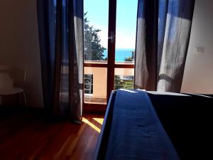 una camera da letto con finestra affacciata sull'oceano di Bressa de Ma affittacamere, room & breakfast a Pietra Ligure
