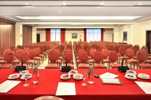 une salle de conférence avec des tables et des chaises rouges dans l'établissement Hotel Aktea, à Lipari