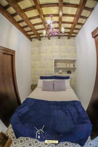 Un dormitorio con una cama azul y blanca y una lámpara de araña. en CASA LOUNA en Vejer de la Frontera