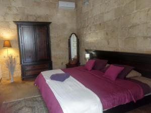 a bedroom with a large bed with purple pillows at Villa Vittoria in Rabat