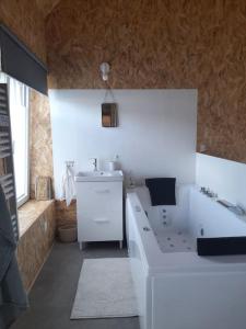 bagno con vasca bianca e lavandino di Maison de village avec cheminée et balnéothérapie a La Ferrière-Harang