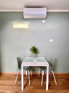 une table et des chaises blanches avec une plante. dans l'établissement La Casina Verde - Appartamento Mansardato, à Livourne