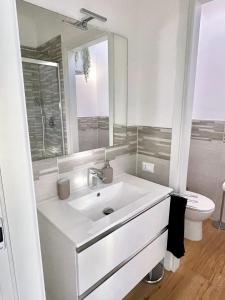 a white bathroom with a sink and a toilet at La Casina Verde - Appartamento Mansardato in Livorno