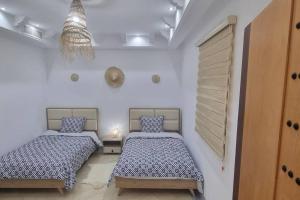 two beds in a room with white walls at Villa des Lotophages in Djerba