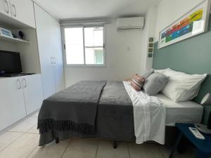 1 dormitorio con cama con almohadas y ventana en Flat com serviço completo e vista Cristo, en Río de Janeiro