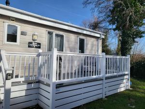 a tiny house with a white fence at Idyllic Lakeview Lodge in Chichester
