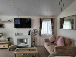 un soggiorno con divano e TV di Idyllic Lakeview Lodge a Chichester