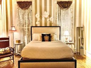 a bedroom with a large bed and a chair at Coppersmith Inn Bed And Breakfast in Galveston