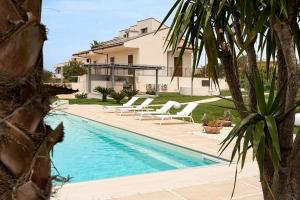 una piscina con sillas blancas y una casa en Villa Paradiso with pool, fireplace & barbeque, en Módica