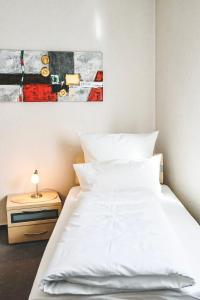 Un dormitorio con una cama blanca y una pintura en la pared en Land.Wein.Gut Pension, en Klingenmünster