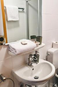 La salle de bains blanche est pourvue d'un lavabo et d'un miroir. dans l'établissement Land.Wein.Gut Pension, à Klingenmünster