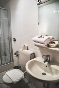 La salle de bains blanche est pourvue de toilettes et d'un lavabo. dans l'établissement Land.Wein.Gut Pension, à Klingenmünster