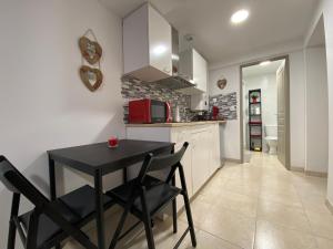 una pequeña cocina con mesa negra y sillas en Studio Centre Ville, en Cambo-les-Bains