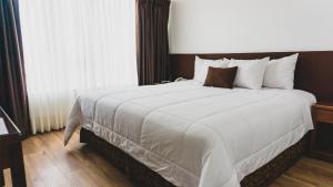 una camera d'albergo con un grande letto con lenzuola bianche di Faraona Grand Hotel a Lima